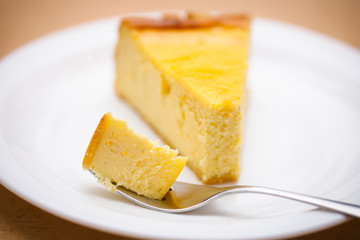 slice of traditional new york cheesecake on white plate on wood table