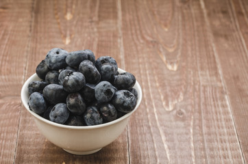 fresh blueberry in a white bowl/fresh blueberry in a white bowl on a wooden background. Copy space