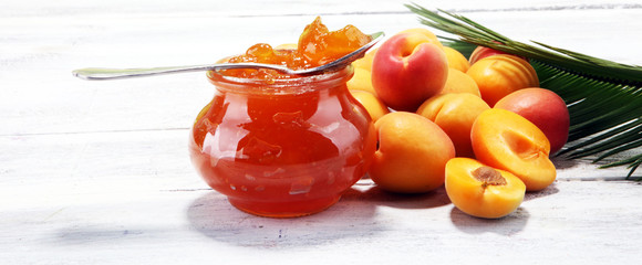 apricot jam and a bunch of fresh apricots on wooden table.