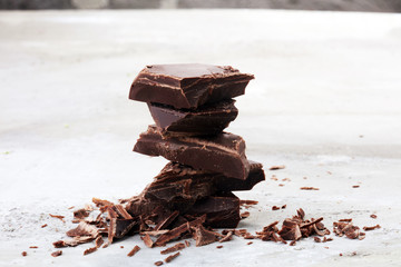 dark chocolate bars on stone table and broken pieces of cocoa