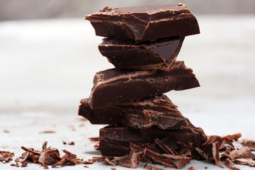 dark chocolate bars on stone table and broken pieces of cocoa