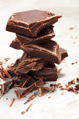 dark chocolate bars on stone table and broken pieces of cocoa
