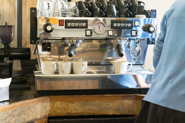 Barista using a coffee maker and prepares cup of coffee for a cu