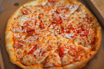 Top view of neapolitan pizza with pepperoni, mozzarella and cherry tomatoes on a white plate for a dinner in italian restaurant. Italy food. Pizza from wooden oven. Close up. Macro.