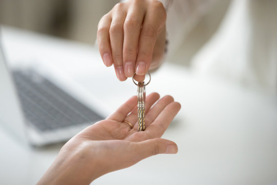 Female hand holding key, woman getting real estate ownership, customer buying new lease rental house becoming first time home owner, property purchase, mortgage investment loan concept, close up view