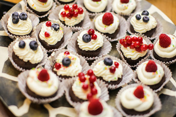 Set of different delicious tasty muffins with berries on summer background. Different dessert tartlets with cream and fresh blueberry and raspberry. Selective focus. candy bar concept