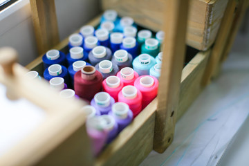 Sewing threads multicolored background closeup / Spools of thread peach color isolated on a white background / wooden casket case / colored thread on a wooden background