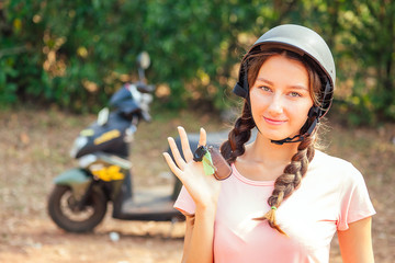 Fototapeta na wymiar beautiful and young woman in a safety helmet sitting on a motorcycle (bike) and holds the keys. concept of safe driving a scooter and renting in Asia