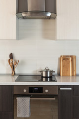 The pan is on a ceramic cooking plate in the new modern kitchen with extractor hood and oven