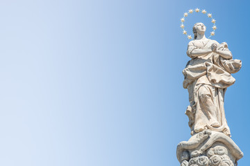 Fototapeta na wymiar Statue of praying lady at Marian Column or Holy Trinity at Hradcanske Square for bubonic plague epidemics in Prague, Czech Republic