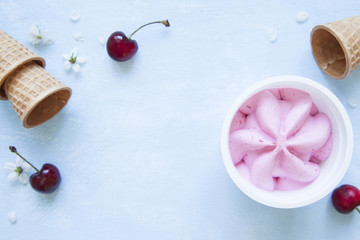 Fototapeta na wymiar Cherry ice cream in plastic jar on blue background.