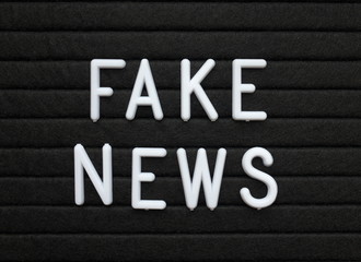 The words Fake News in white plastic letters on a black letter or bulletin board
