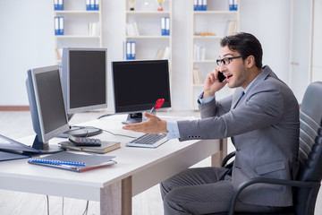 Businessman sitting in front of many screens