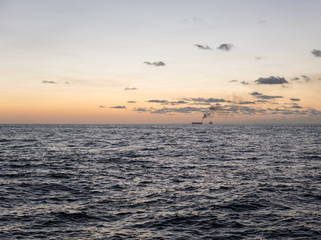Sunset at sea. Offshore oil and gas industry, sea oil production and storage on background.