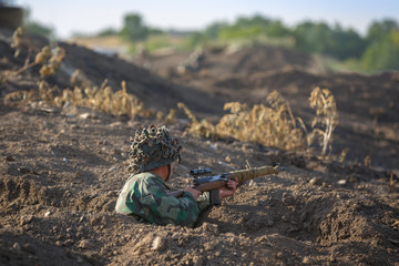 Soldier with a sniper rifle is in a trench