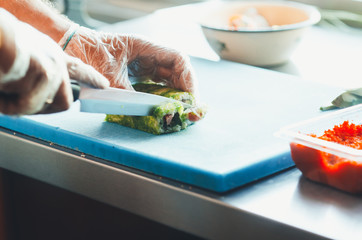 professional chef, chef the process of making sushi rolls, spins bamboo Mat and cut slices