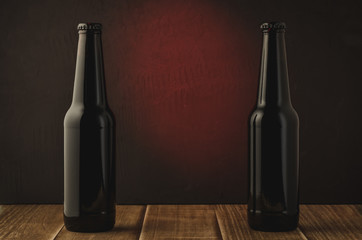 two black bottle of beer on a red background of a wooden shelf/two black bottle of beer on a red background of a wooden shelf. Selective focus and copyspace