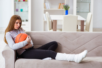Fototapeta premium Young woman with broken leg at home