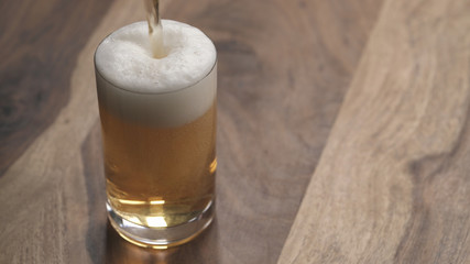 closeup pour ginger beer in a glass on wood table
