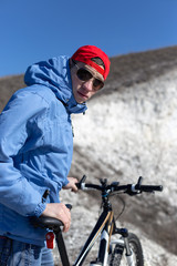 Young guy with a bicycle on a chalky mountain