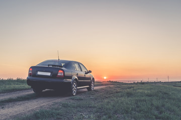 Fototapeta na wymiar Black car on the road at sunset
