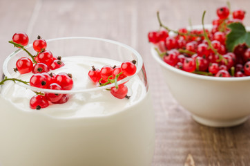 yogurt with red currant in glass on a wooden backgroundyogurt with red currant in glass on a wooden background. selective focus.
