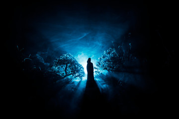 Horror Halloween decorated conceptual image. Alone girl with the light in the forest at night....