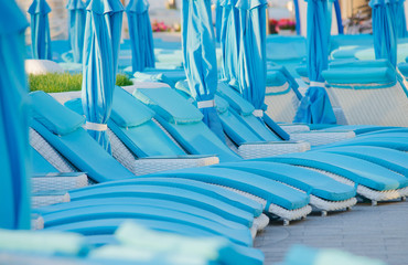 A beach of a hotel with blue empty sunbeds