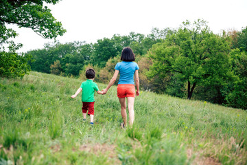 Fototapeta premium The boy walks with his mother in the meadow.