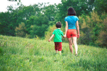 The boy walks with his mother in the meadow.