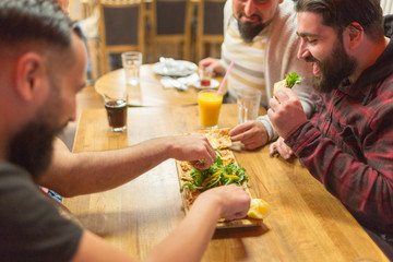 Men in restaurant eating Turkish Lahmacun, Armenian pizza. Selective focus