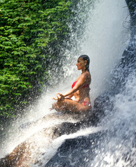 young attractive and happy 30s woman with fit body practicing yoga wet under tropical paradise waterfall stream in meditation and relaxation