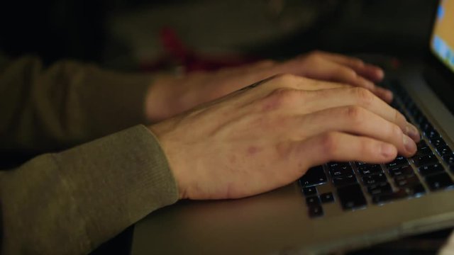 Close up of male hands typing text or programming code in computer in natural ambient light at late evening. Stock
