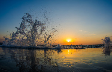 A beautiful vibrant seascape at the sunrise. The sky is reflected in a mirror alike water. Water splashes on both sides of the picture