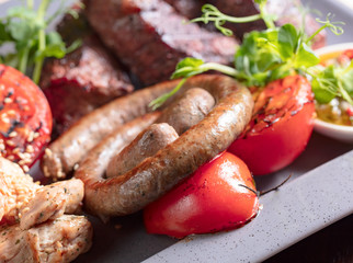 Assorted delicious grilled meat and sausages with vegetables .