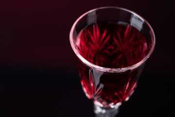 Close-up of crystal glass with red wine on dark background.