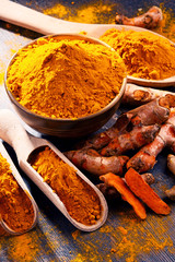 Composition with bowl of turmeric powder on wooden table