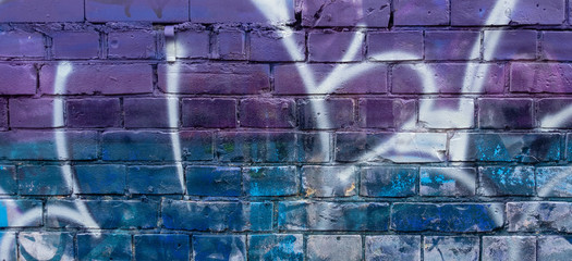Fragment of colorful graffiti drawing made with aerosol paints on a brick wall