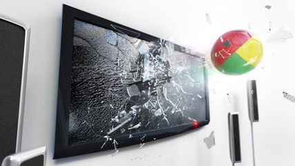 Soccer ball with the flag of Guinea-Bissau kicked through a shattering tv screen.(3D rendering series)
