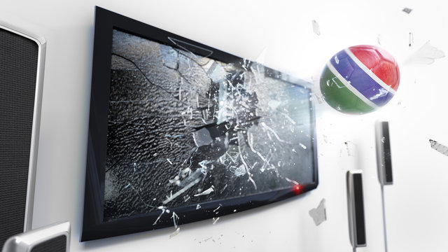 Soccer ball with the flag of Gambia kicked through a shattering tv screen.(3D rendering series)