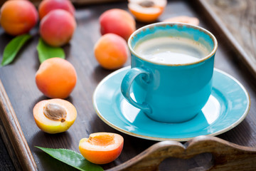 Delicious coffee with foam and plums on wooden tray