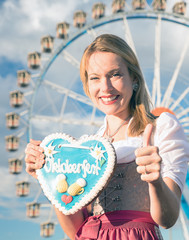 young sexy woman is doing oktoberfest in munic summer, spring folk festival she is wearing a dirndl and holding a hear brezn in her hand