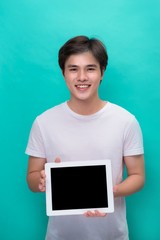 Smiling asian man showing blank tablet computer screen over blue background