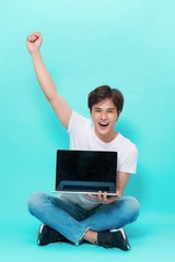 A happy excited young asian man with a laptop  and celebrating success