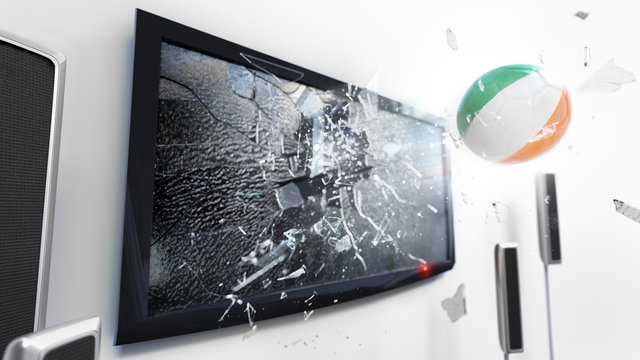 Soccer ball with the flag of Ireland kicked through a shattering tv screen.(3D rendering series)