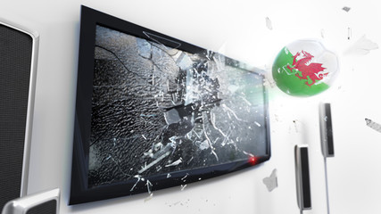 Soccer ball with the flag of Wales kicked through a shattering tv screen.(3D rendering series)