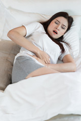 Obraz na płótnie Canvas woman with stomach ache on bed