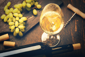 A glass of white wine and green grapes on wooden background - obrazy, fototapety, plakaty