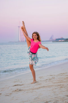 Cute young girl doing yoga at the beach