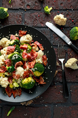 Steamed Broccoli, Cauliflower Salad with Bacon, parmesan cheese in a black plate. healthy food concept